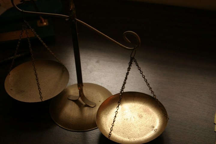 Antique brass balance scale with chains on a dark surface.
